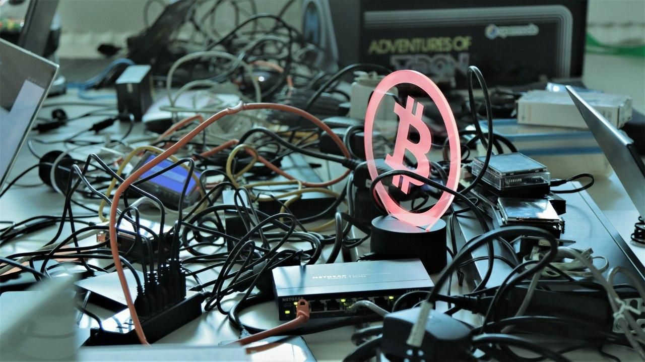 Vollgestellter Computertisch mit Bitcoin Zeichen
