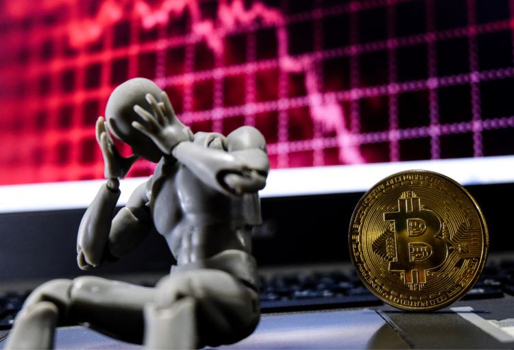 Kleine Actionfigur hält sich den Kopf neben einer Bitcoin Münze